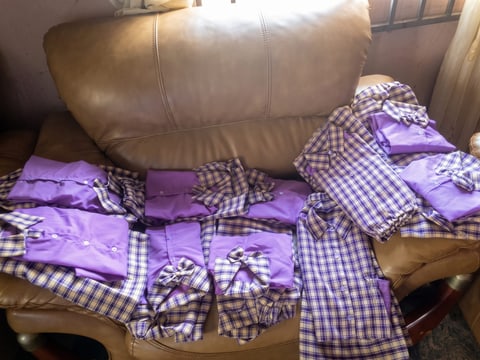 New purple gingham school uniforms laid out on a sofa