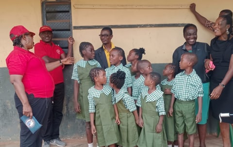 Children in new uniforms chatting and smiling with volunteers and teachers