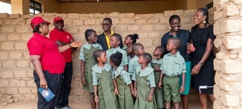 Fidelstine volunteers with children in new school uniforms outside a classroom