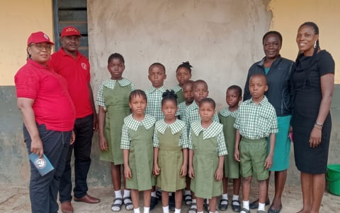 Children of the home in new green gingham school uniforms, with Fidelstine volunteers and staff