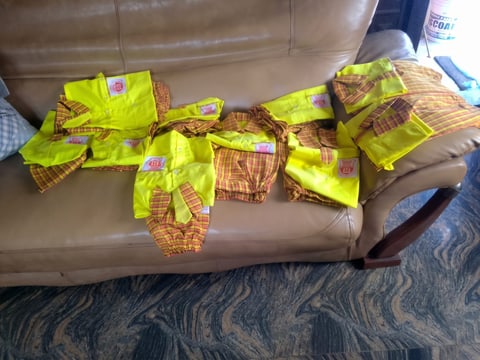 New yellow and checked school uniforms laid out on a sofa